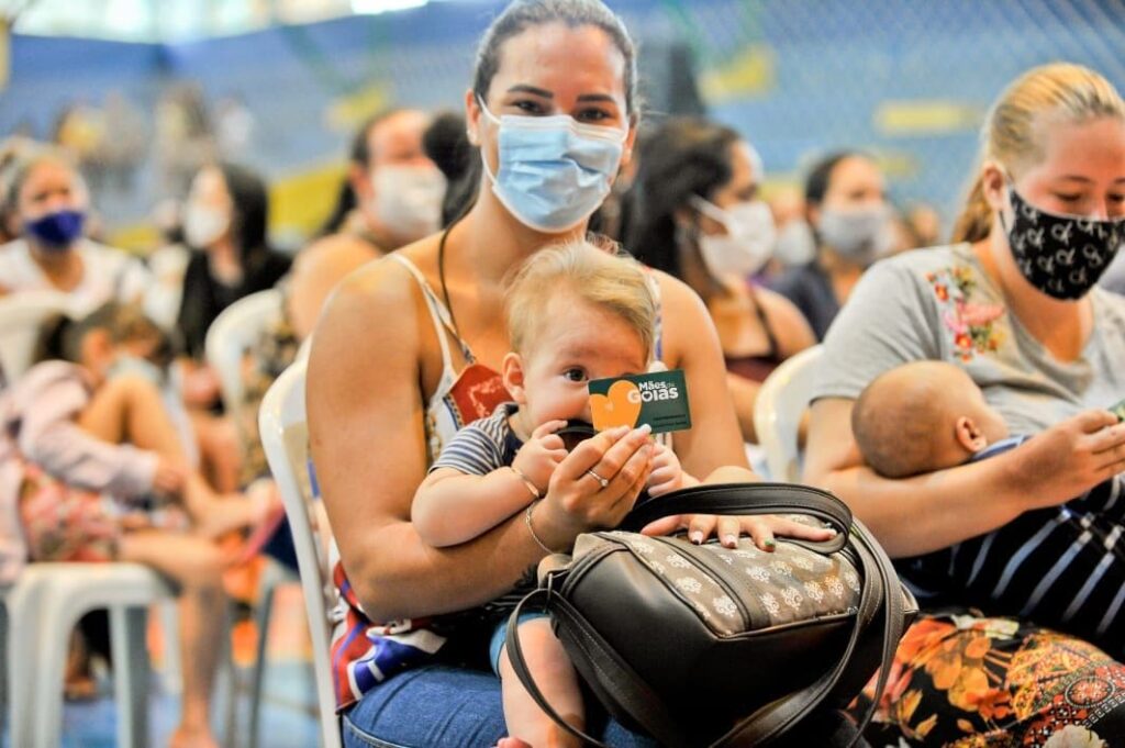 Uma nova direção foi dada aos programas sociais do Governo de Goiás nos últimos três anos. Com viés humanitário, característico de sua formação como médico, o governador Ronaldo Caiado cumpre o compromisso de levar apoio e assistência aos goianos em situação de vulnerabilidade econômica e alimentar. Somente para atender essa população, foi destinado R$ 1,3 bilhão em investimentos com medidas que alcançam os 246 municípios goianos. “Nossa gestão não é para construir grandes prédios. A nossa grande obra é cuidar das pessoas”, afirmou. Para suprir direitos básicos, como a alimentação, Caiado conduz uma gestão que deu fim a um período de inércia, com a distribuição de mais de 1 milhão de cestas básicas (1.019.442) pela Organização das Voluntárias de Goiás (OVG), iniciada neste mandato, além de ter realizado repasse de R$ 33 milhões diretamente às prefeituras, a maior destinação do País neste setor. Enquanto a gestão anterior não cumpriu com obrigações, fator evidenciado em dívidas deixadas em programas como o Bolsa Universitária, que apresentava um débito de R$ 76 milhões, Caiado encabeçou movimento de recuperação das contas e reconquista da credibilidade do governo. Somente no Bolsa Universitária, a administração estadual apresentava dívida com 82 instituições de ensino superior. Foi necessária a renegociação e, atualmente, R$ 69 milhões de atrasos já foram sanados. O Programa Universitário do Bem (ProBem) substituiu o Bolsa Universitária e já alcançou 10 mil estudantes que precisam de apoio para seguir na carreira acadêmica. Coordenadora do Gabinete de Políticas Sociais e presidente de honra da OVG, a primeira-dama Gracinha Caiado destaca que as ações sociais são pautadas por critérios técnicos e a prioridade é fazer uma diferença real na vida das pessoas. “Desde o início de 2019, o governador Ronaldo Caiado decidiu trabalhar com o Índice Multidimensional de Carência das Famílias Goianas, cálculo feito pelo Instituto Mauro Borges com base em dados do CadÚnico. Desta forma, podemos identificar aquelas famílias mais vulneráveis e quais são suas reais necessidades. Não nos permitimos fazer política com benefícios sociais. Nosso papel é garantir que os programas do governo cheguem a quem realmente mais precisa”, explicou. A guinada nos programas sociais foi pautada pela aplicação de base científica para atender pessoas que realmente precisam de apoio governamental. O cenário encontrado era de mero assistencialismo, sem critérios consolidados. Um dos destaques é o Programa Mães de Goiás, idealizado pelo governador Ronaldo Caiado, que assegura auxílio mensal de R$ 250 para 100 mil mães em todo o Estado. O investimento total é de R$ 219 milhões, viabilizados pelo Fundo de Proteção Social do Estado de Goiás (Protege Goiás). Até o momento, a entrega dos cartões foi efetuada em 92 municípios, e 71 mil mulheres com filhos menores de seis anos já foram contempladas. A meta é atingir 100 mil. A medida supre uma lacuna de apoio às crianças em idade pré-escolar ao garantir recursos para itens básicos como alimentação e medicamentos. “Nós vamos ajudar a criança da hora que ela nasce até os 6 anos de idade”, declarou Caiado ao citar que, após essa idade, a família encontra amparo também nas instituições de ensino. Entre outras propostas mais recentes e que transformaram as modalidades de proteção social instituídas pelo Governo de Goiás estão o Crédito Social, que viabilizou R$ 20 milhões para auxiliar a recuperação econômica do Estado; o Programa de Dignidade Menstrual, destinado a atender 146 mil mulheres; e o Água Social, implementado para subsidiar até 80% da fatura de água de famílias vulneráveis, com propósito de atender 128 mil pessoas. Com a ausência de programas para auxiliar o custeio de aluguel de famílias endividadas e estudantes sem recursos financeiros suficientes para custear moradia, foi implantado o Programa Pra ter Onde Morar - Aluguel Social, com abrangência a 30 mil famílias que recebem R$ 350 por mês para pagar locação de imóvel. O Governo de Goiás promove ainda ações como a construção de moradias a custo zero. São 1.156 construídas e entregues gratuitamente à população em 30 municípios goianos, um investimento de mais de R$ 130 milhões. O Programa Aprendiz do Futuro ganhou novo formato, com modelo de destaque internacional que usa mais tecnologia e amplia benefícios aos contemplados. Agora são 5 mil adolescentes selecionados nos 246 municípios goianos. Além da bolsa mensal de R$ 516, com direito a 13° salário, a proposta inclui cursos, recebimento de tablets e vale-alimentação de R$ 150, além de vale transporte, seguro de vida e materiais de identificação como uniformes e crachá. “Isso é o que eu chamo de um governo humanitário, um governo não interesseiro”, definiu Caiado ao listar as ações que protagonizaram seu mandato na área social. O governador defende que o objetivo maior é dar possibilidades de mudança de vida às pessoas. “Esse é o nosso objetivo: dar dignidade e, ao mesmo tempo, estimular a educação, quebrar o ciclo da pobreza, no sentido de as pessoas terem melhor perspectiva de vida no futuro”, reforçou. OVG A doação de cestas básicas foi instituída nesta gestão e intensificada diante da situação de emergência sanitária mundial pela Covid-19. Em atenção a todos municípios goianos, a Campanha de Combate à Propagação do Coronavírus já doou 1 milhão e 19 mil cestas de alimentos do lote de mais de 1 milhão de kits de alimentos encomendados, 465 mil frascos de álcool em gel e mais de 1,8 milhão de equipamentos de proteção individual (EPI). O Banco de Alimentos também passou por revitalização completa. O ambiente, antes sem revestimento ou climatização, apresentava condições ruins para acondicionar mantimentos e pouco controle de entrada e saída de itens. A falta de organização geral também era configurada pela ausência de cadastro de famílias e entidades beneficiadas, com cerca de 100 atendimentos mensais. Nesta gestão, o Banco de Alimentos passou a ser gerido pela OVG. A partir disso, recebeu um novo prédio, com estrutura adequada, e beneficia 250 instituições e mais de 2.500 famílias. O volume de doações soma 3,6 mil toneladas de frutas, verduras e legumes, com alcance médio de 45 mil pessoas. Hoje, a média de atendimentos é 10 vezes maior: 1.000 famílias por mês. Na gestão de Ronaldo Caiado, foi criado o Programa NutreBem, lançado em outubro de 2021. A iniciativa viabiliza o Mix do Bem, alimento de rápido preparo destinado a famílias em situação de vulnerabilidade social, e também produzirá legumes embalados a vácuo e frutas desidratadas que serão destinados aos municípios mais longínquos do Estado. Já o Restaurante do Bem foi entregue pela gestão anterior com uma dívida de R$ 4,5 milhões junto às empresas gestoras do então Restaurante Cidadão. Sempre atento a manter os compromissos em dia, Caiado quitou os débitos, e os pagamentos passaram a ocorrer rigorosamente dentro do previsto. A soma de refeições servidas, em 13 unidades, é de mais de 9 milhões nos primeiros anos do atual governo. Desde o início da pandemia, a OVG serve marmitas para pessoas em situação de rua em Goiânia e Luziânia, além de atender refugiados venezuelanos. Já foram doadas mais de 178 mil refeições. A entrega de benefícios sociais à população que mais precisa também recebeu atenção nos últimos três anos. Famílias que buscam cadeiras de rodas, enxoval de bebê, muletas, entre outros itens, passaram a contar com materiais de melhor qualidade e em maior quantidade para atender a mais pessoas. Desde o início da atual administração, foram doados 318 mil benefícios em Goiás. Agora, os goianos também têm à disposição uma unidade itinerante da OVG, antes inexistente. O formato garante atendimento presencial e destinação de benefícios para a população onde ela estiver. A equipe, que se desloca para os 246 municípios de Goiás, também presta informações sobre como ter acesso aos serviços do governo. Em outra frente, a Vila Vida, local que oferece atendimento e moradia a idosos, apresentava problemas de infraestrutura, assim como as Casas-Lares. Para sanar os problemas, a unidade recebeu a primeira reforma, desde a sua fundação em 1994. O investimento foi de R$ 1,2 milhão. GPS O Governo de Goiás passou a atuar estrategicamente junto às comunidades mais carentes em Goiás, fato que não ocorria em anos anteriores. Por meio do Gabinete de Políticas Sociais (GPS), coordenado pela primeira-dama, Gracinha Caiado, foi possível articulação direta com os municípios e promover uma rede de trabalho em parceria com as gestões municipais para levar benefícios de maneira pontual. Um dos destaques foi a atenção à comunidade Kalunga, garantida mesmo nas regiões de difícil acesso. Entre 2019 e 2021, foram investidos mais de R$ 25 milhões para construção de rede elétrica, benefício direto a 350 famílias. Os moradores da área receberam ainda energia fotovoltaica e abastecimento de água. As comunidades Kalunga também foram beneficiadas com projetos que chegaram a outras partes do Estado, como o Goiás Social, o projeto da cerveja de mandioca, os laboratórios Include, a entrega de cestas básicas, além da instalação de internet via satélite nas escolas locais. Juntamente com a Gerência Social da OVG, o Gabinete de Políticas Sociais também realiza um trabalho de estudos e capacitação técnica junto às primeiras-damas e gestores de Assistência Social dos municípios goianos, contribuindo para articulação de ações e organização da proteção do social em todo o Estado. O Gabinete de Políticas Sociais contribui para a implementação do programa Alfabetização e Família, executado pela Secretaria de Educação (Seduc), que promove a alfabetização de jovens e adultos em vulnerabilidade social e já atende mais de 300 alunos em 10 municípios goianos. Outra frente de trabalho é o Agro é Social, com apoio da Emater e da Secretaria de Agricultura, Pecuária e Abastecimento (Seapa), o Gabinete de Políticas Sociais já realizou a entrega de sementes a famílias rurais em situação de vulnerabilidade, juntamente com auxílio na capacitação e acompanhamento técnico, promove cursos de capacitação em municípios do interior do Estado, além do investimento em tanques, alevinos, insumos e equipamentos para o beneficiamento da cadeia produtiva da piscicultura em Minaçu. Direitos Humanos A partir de 2019, o Estado de Goiás assumiu um posicionamento de combate à violência contra a mulher em diversas iniciativas que foram implementadas em linha contrária à condução do governo anterior, que fechou a Secretaria da Mulher e da Igualdade Racial. Na gestão Caiado, houve a sanção do Pacto Goiano pelo Fim da Violência Contra a Mulher; a adesão ao Dia Laranja; e a criação da Rede Estadual Pelo Fim da Violência Contra a Mulher e do Batalhão Maria da Penha da Polícia Militar de Goiás. A busca por proteger a dignidade das pessoas, com ações na área de direitos humanos, também recebeu outra atenção nos últimos anos. Não havia uma estrutura para realização de projetos e ações específicas para o setor. Para solucionar o problema, a atual gestão integrou diferentes órgãos estaduais e entidades do terceiro setor em uma estrutura especialmente criada para atender demandas básicas como facilitar acesso a documentação como registro de nascimento, além de ter efetivado o Conselho Estadual de Direitos Humanos, Igualdade Racial e Combate ao Preconceito.