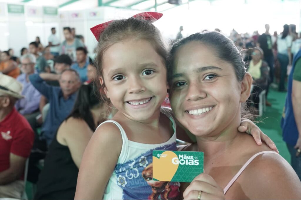 Mulher e criança seguram cartão Mães de Goiás