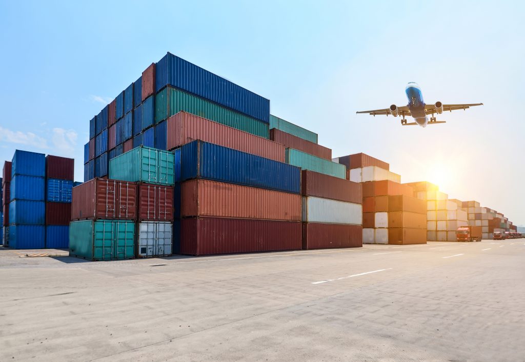 Economia moderniza sistema de controle de importações em Goiás - Contêiners empilhados e avião sobrevoando-os