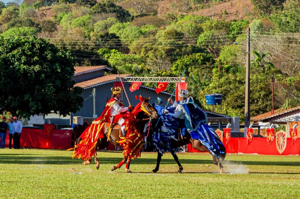 Santa Terezinha de Goiás recebe 68ª edição das Cavalhadas neste fim de semana -cavaleiros com figurinos demouros e cristãos e montados a cavalo, ao fundo da imagem serra verdejante
