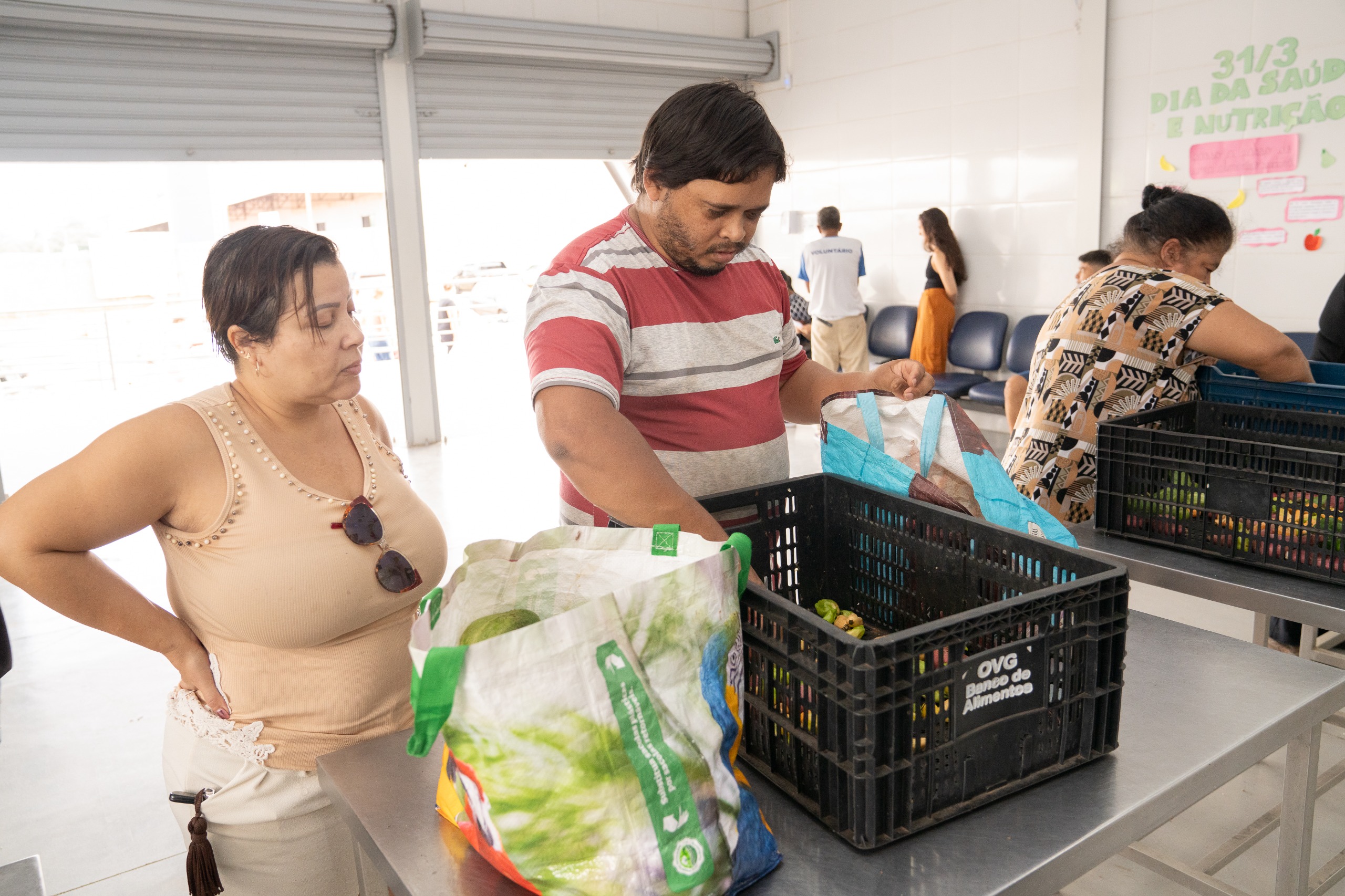 Banco de Alimentos da OVG orienta famílias sobre cadastro para receber alimentos semanalmente - Pessoas recebendo alimentos no Banco de Alimentos